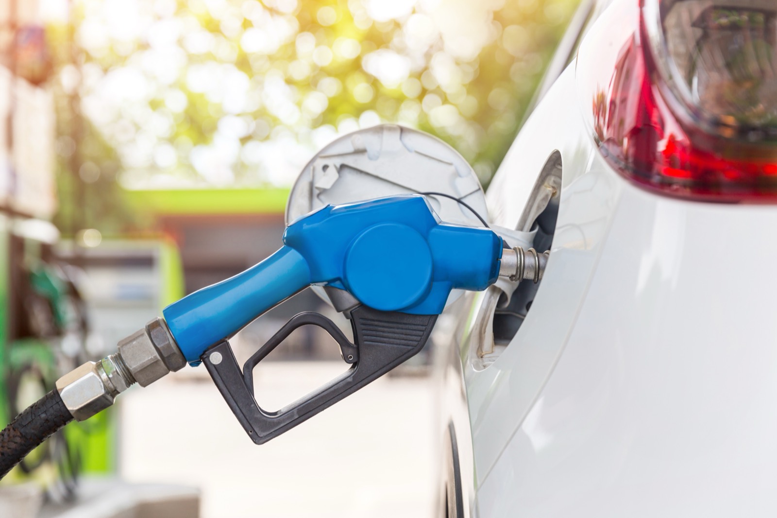 Pistola de combustible cargando el tanque de un carro en una gasolinera.
